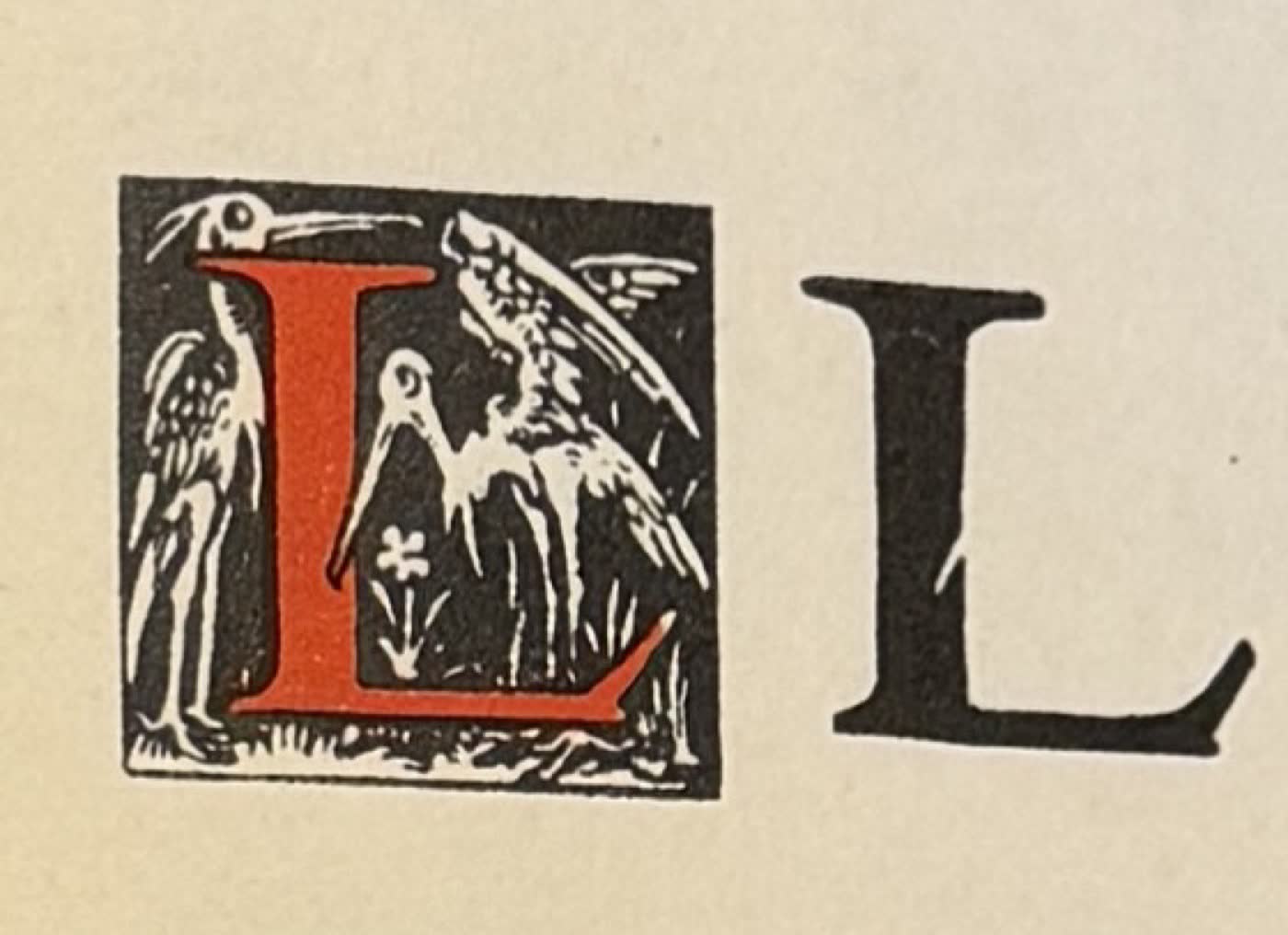 A red initial L surrounded by two birds, next to a plain black L